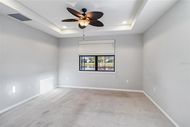 unfurnished room featuring light carpet, a raised ceiling, and ceiling fan