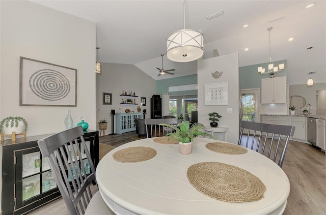 dining space featuring lofted ceiling, ceiling fan with notable chandelier, and light wood-type flooring