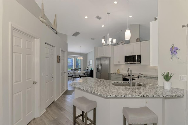 kitchen with a kitchen breakfast bar, kitchen peninsula, pendant lighting, stainless steel appliances, and white cabinets