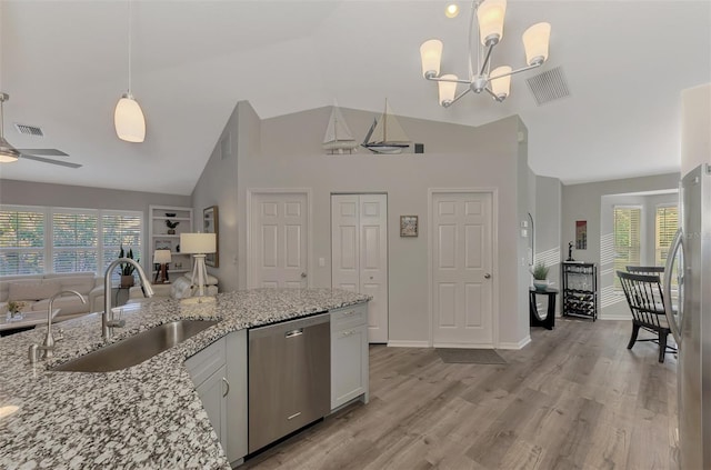 kitchen with sink, hanging light fixtures, appliances with stainless steel finishes, light stone countertops, and white cabinets