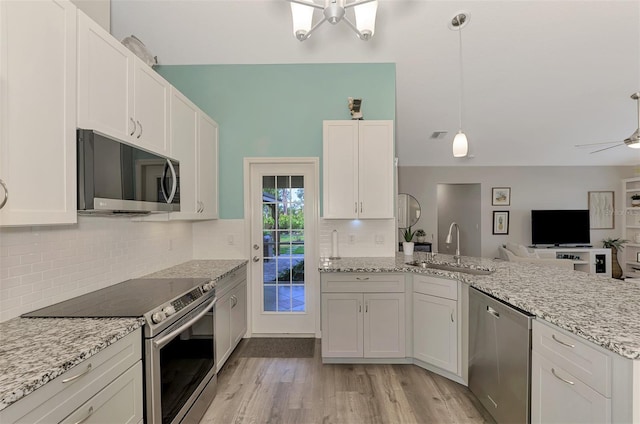 kitchen featuring appliances with stainless steel finishes, white cabinetry, sink, decorative backsplash, and hanging light fixtures