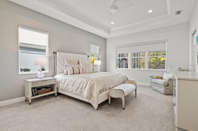 carpeted bedroom featuring ceiling fan and a raised ceiling