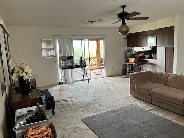 living room featuring ceiling fan and a textured ceiling