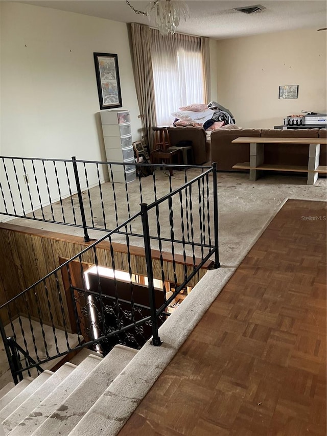 stairway featuring parquet floors and a notable chandelier