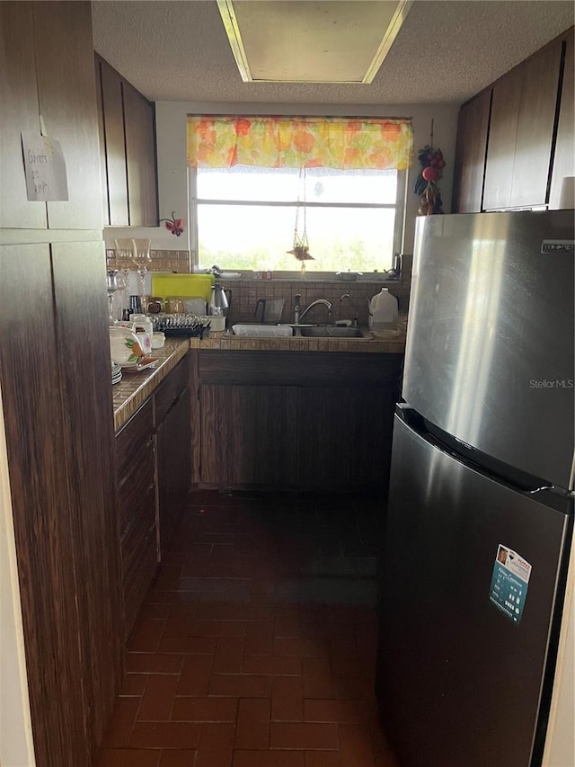 kitchen with plenty of natural light, stainless steel fridge, and dark brown cabinets