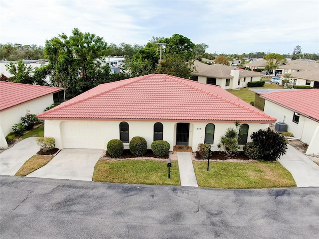 mediterranean / spanish-style house with a garage, a front lawn, and central AC