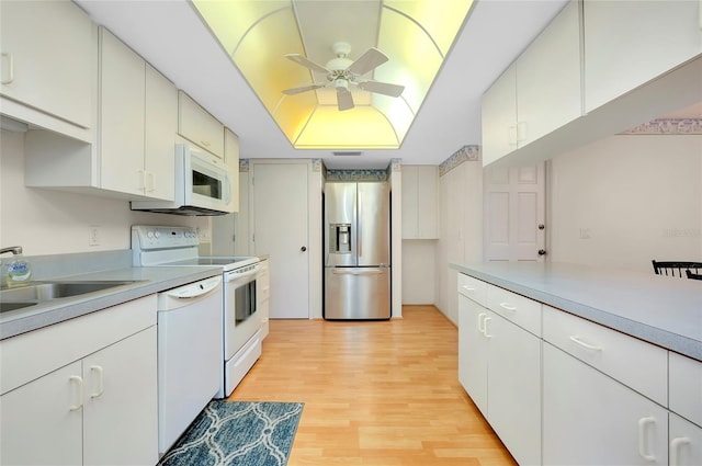 kitchen with white appliances, white cabinets, light hardwood / wood-style floors, sink, and ceiling fan