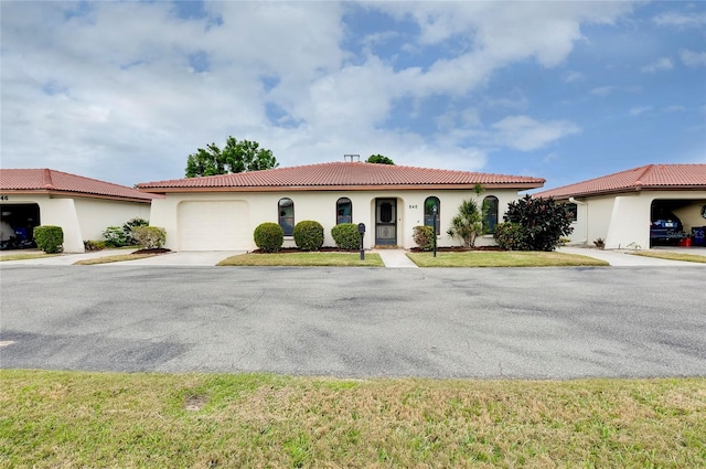 mediterranean / spanish-style home with a garage and a front lawn