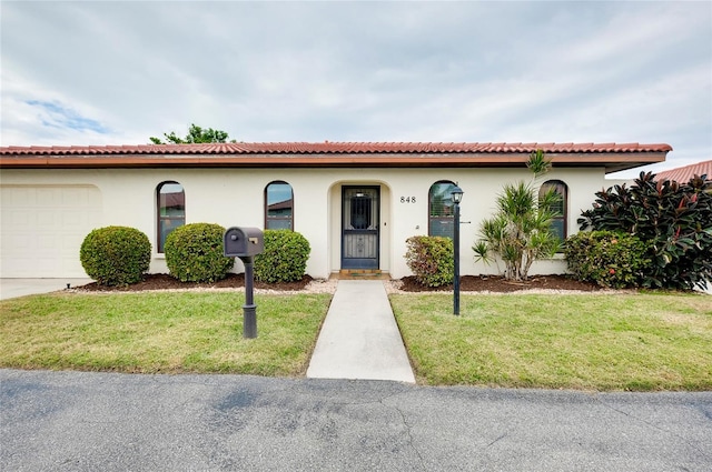 mediterranean / spanish-style home with a garage and a front lawn