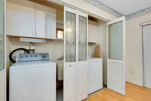 laundry area with light hardwood / wood-style floors, cabinets, and washer and dryer