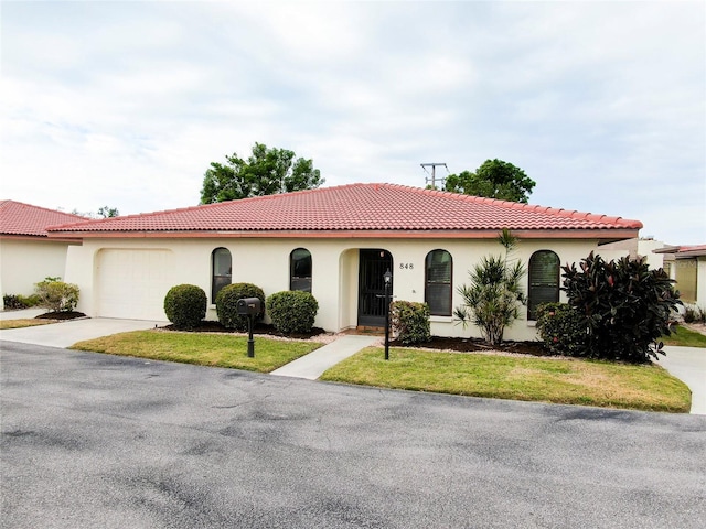 mediterranean / spanish house featuring a garage and a front yard