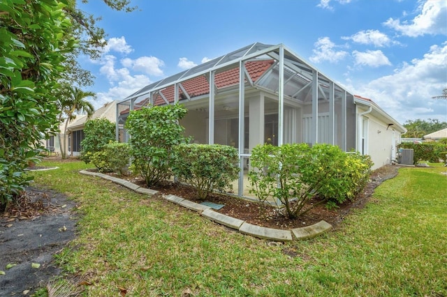 view of side of home featuring cooling unit, a lanai, and a yard