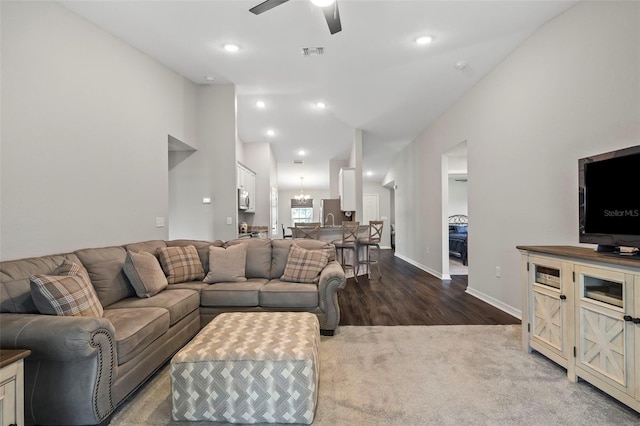 carpeted living room featuring ceiling fan with notable chandelier