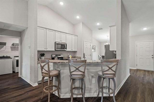 kitchen featuring a breakfast bar, light stone counters, kitchen peninsula, stainless steel appliances, and white cabinets