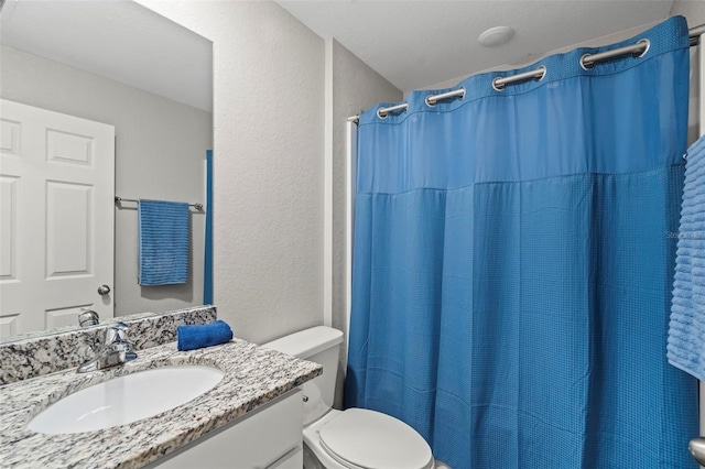 bathroom featuring vanity, walk in shower, and toilet