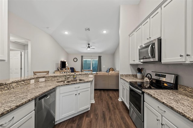 kitchen with stainless steel appliances, open floor plan, white cabinets, and a sink