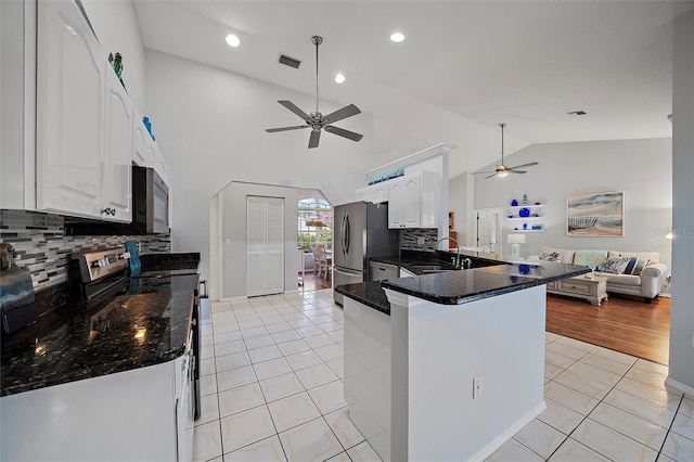 kitchen featuring kitchen peninsula, appliances with stainless steel finishes, white cabinetry, light tile patterned floors, and decorative backsplash