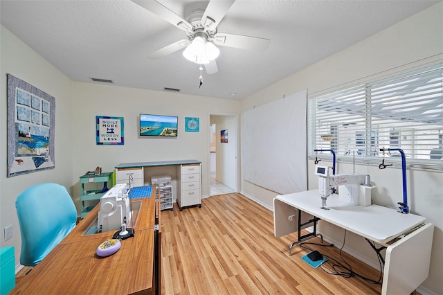 office area with light wood-type flooring, a textured ceiling, and ceiling fan