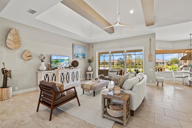 living room with a tray ceiling and ceiling fan with notable chandelier