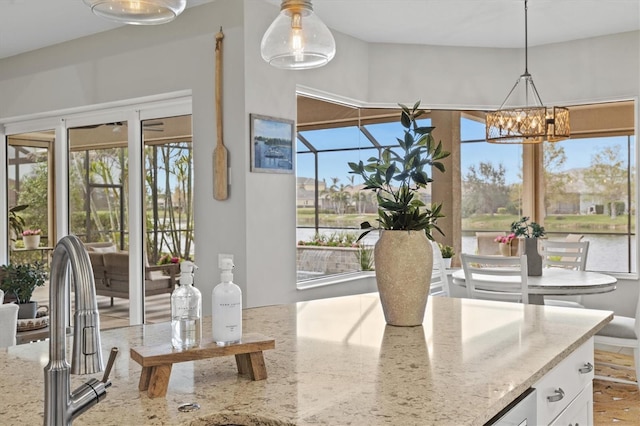 kitchen featuring white cabinetry, decorative light fixtures, and light stone counters