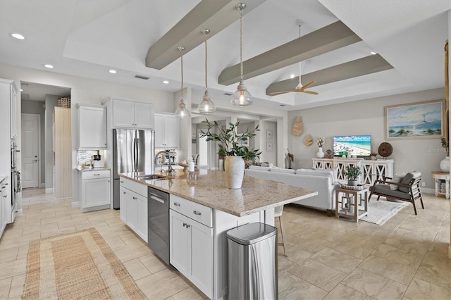 kitchen featuring white cabinetry, decorative light fixtures, a center island with sink, a tray ceiling, and stainless steel appliances