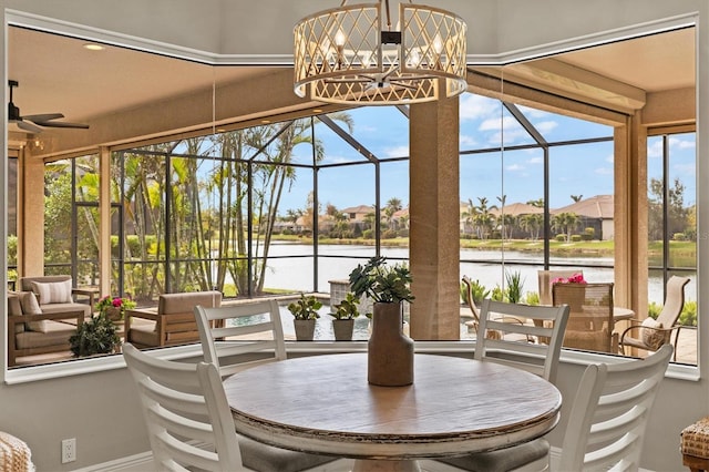 sunroom / solarium with a water view and ceiling fan with notable chandelier