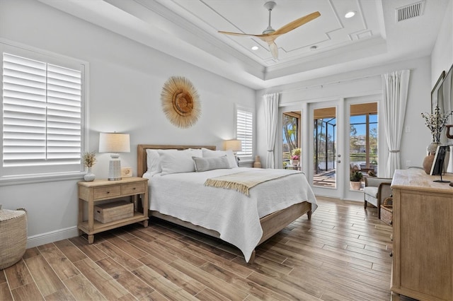 bedroom featuring multiple windows, a tray ceiling, access to outside, and ceiling fan