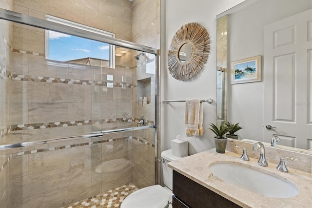 bathroom with vanity, a shower with shower door, and toilet