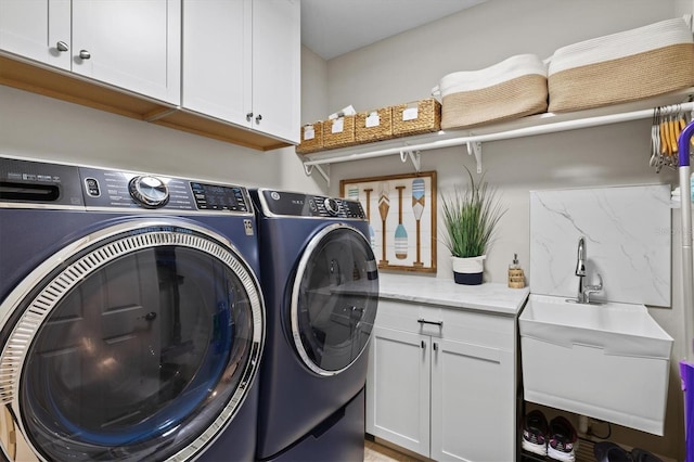 clothes washing area with sink, washer and clothes dryer, and cabinets