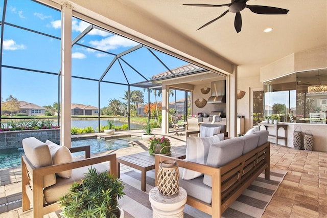 view of patio / terrace featuring ceiling fan, glass enclosure, a water view, an outdoor living space, and pool water feature