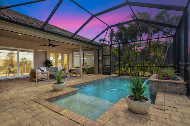 pool at dusk featuring ceiling fan, an outdoor hangout area, a patio, and a lanai