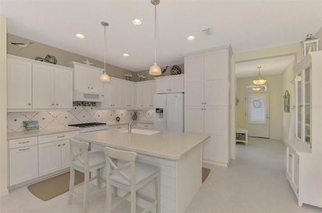 kitchen with decorative light fixtures, sink, white appliances, and white cabinets