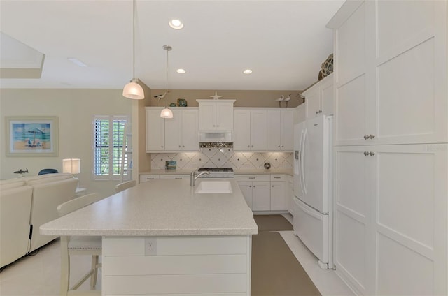 kitchen featuring white fridge with ice dispenser, white cabinetry, a kitchen island with sink, and sink