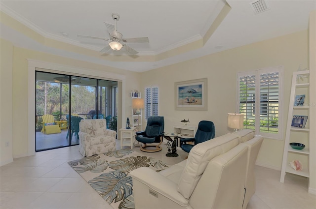 tiled living room featuring ceiling fan, a raised ceiling, crown molding, and a healthy amount of sunlight