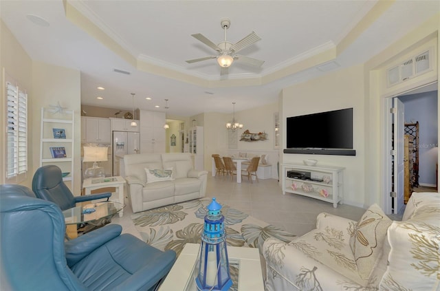 tiled living room featuring ceiling fan with notable chandelier, ornamental molding, and a tray ceiling