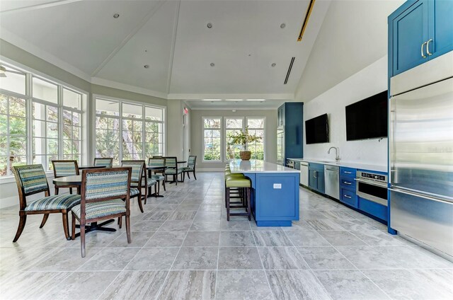 kitchen with a center island, blue cabinetry, sink, stainless steel appliances, and a breakfast bar area