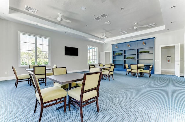 carpeted dining room featuring ceiling fan, plenty of natural light, and a raised ceiling