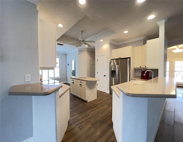 kitchen featuring a wealth of natural light, white cabinets, sink, kitchen peninsula, and crown molding