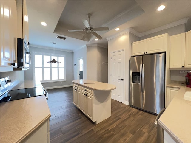 kitchen with white cabinets, a kitchen island, decorative light fixtures, stainless steel appliances, and a tray ceiling