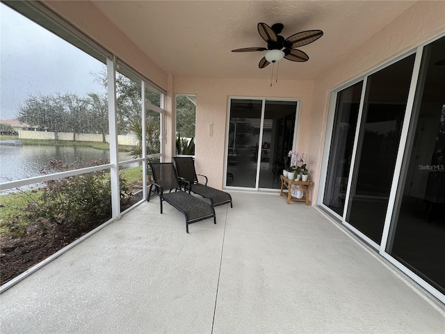 sunroom / solarium featuring a water view and ceiling fan