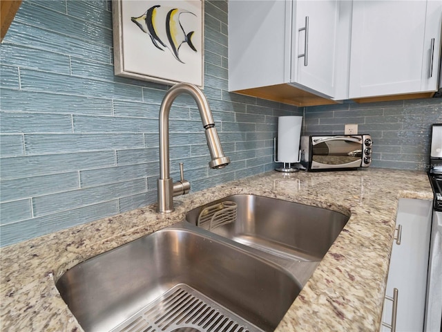 1423 Avenida Del Circo Unit 1C, Venice, FL 34285 - kitchen view of a sink, tasteful backsplash, light stone counters, and white cabinetry