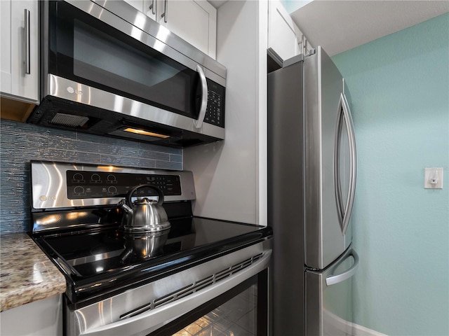 1423 Avenida Del Circo Unit 1C, Venice, FL 34285 - kitchen featuring appliances with stainless steel finishes, backsplash, white cabinetry, and baseboards
