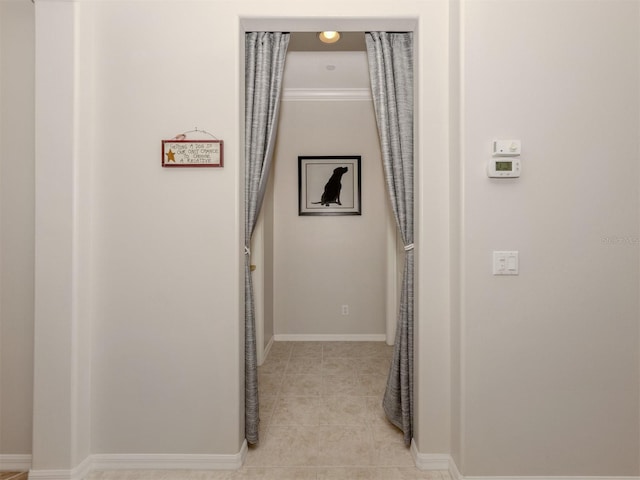 corridor with crown molding and light tile patterned floors