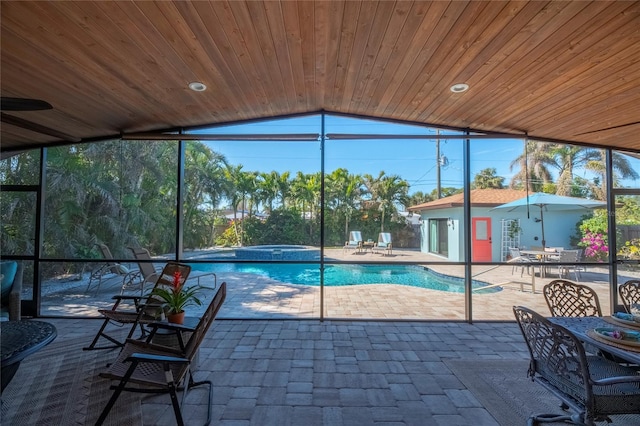 view of swimming pool with an in ground hot tub, glass enclosure, an outdoor structure, and a patio