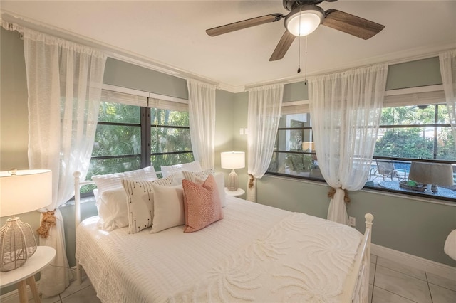 tiled bedroom with ornamental molding and ceiling fan