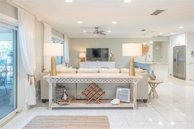 living room with crown molding, ceiling fan, sink, and light tile patterned floors