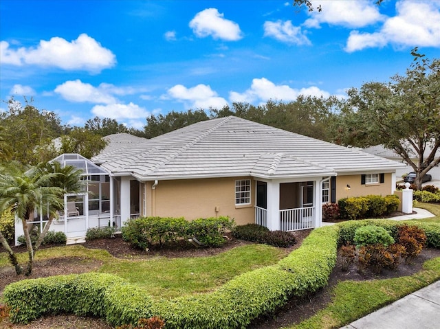 single story home featuring a front yard, stucco siding, a tile roof, and a lanai