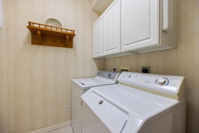 clothes washing area with cabinet space, wallpapered walls, baseboards, tile patterned floors, and washing machine and clothes dryer