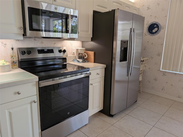 kitchen featuring stainless steel appliances, light tile patterned floors, light countertops, and wallpapered walls