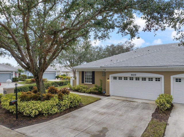 ranch-style house with a garage, driveway, a tiled roof, and stucco siding